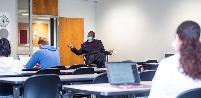 波士顿州立大学的Walter Harper教授坐在教室的前面讲课，而学生们则坐在一排排的桌子旁，打开笔记本电脑